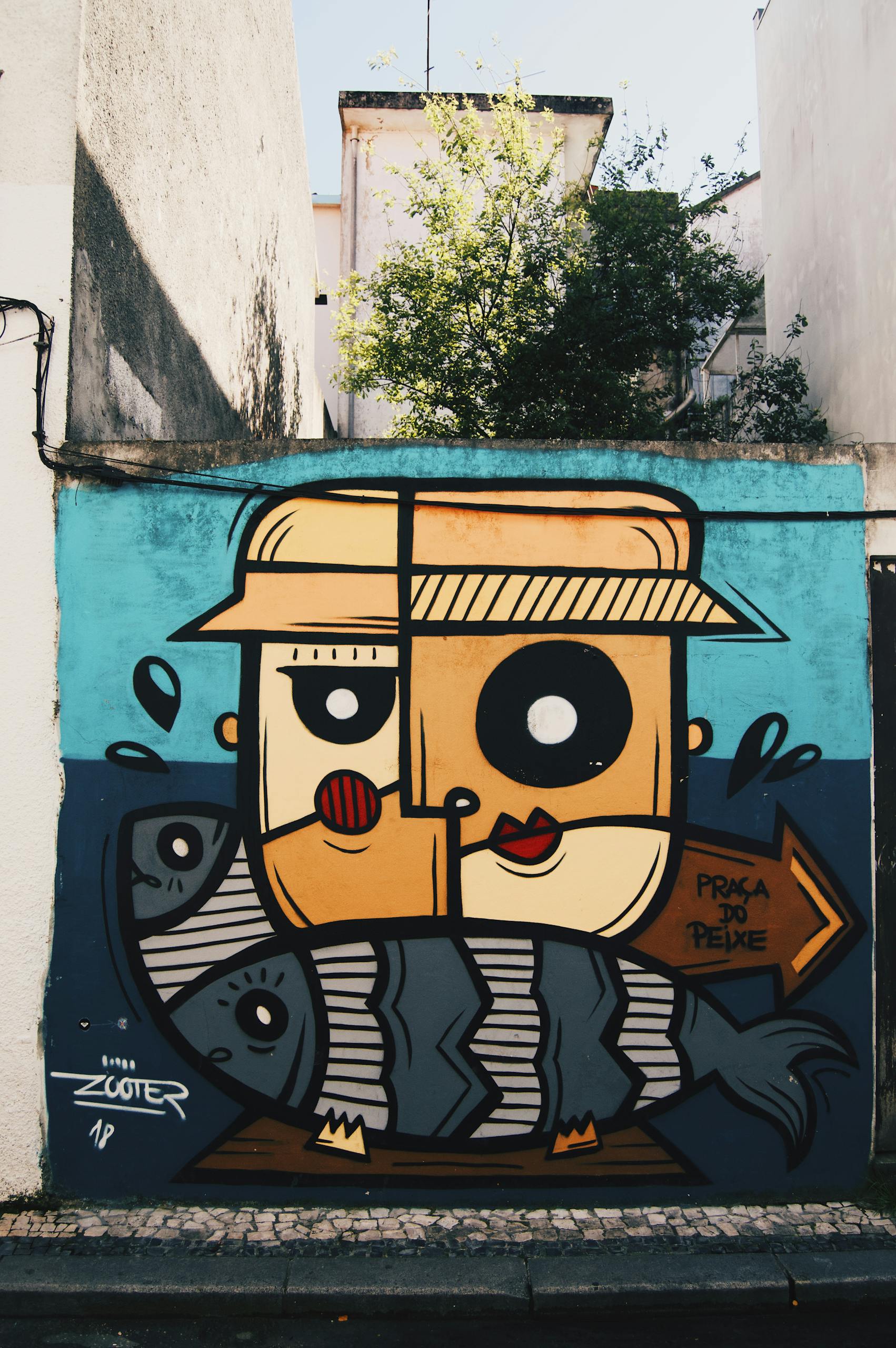 Vibrant street art depicting cartoonish faces and fish on an urban wall.
