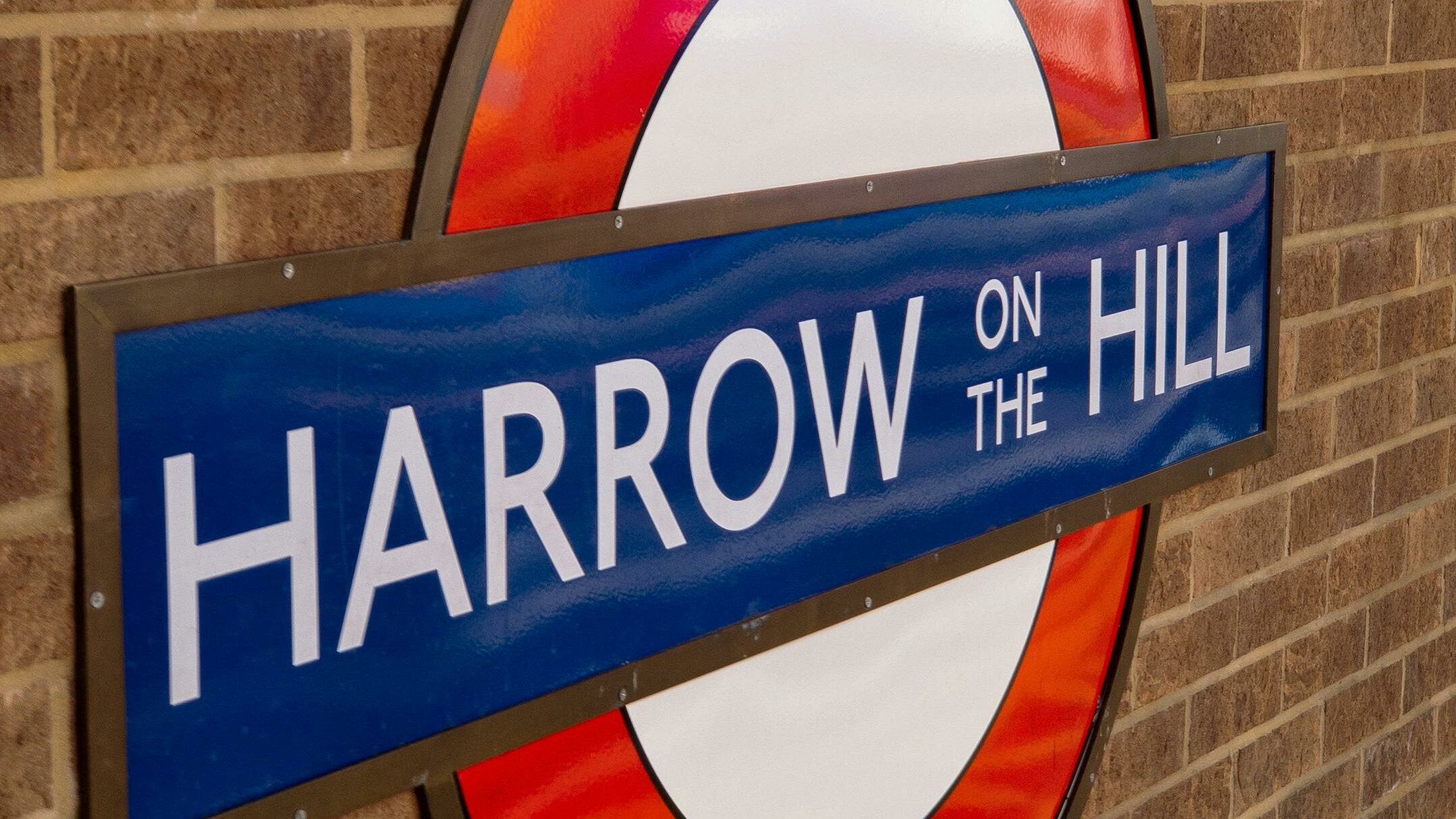 Close-up of Harrow on the Hill tube station sign on London's underground, showcasing iconic design.